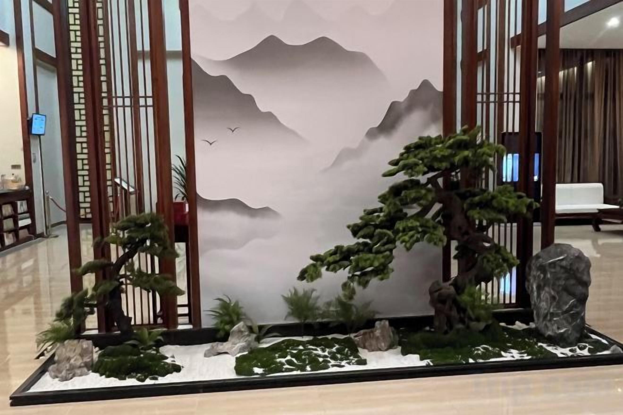 A traditional Japanese-style indoor garden with a rock, a bonsai tree, and a small pond.