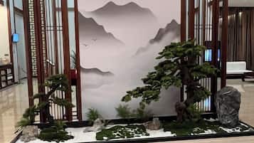 A traditional Japanese-style indoor garden with a rock, a bonsai tree, and a small pond.