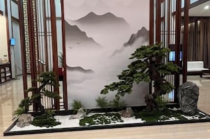 Un jardín interior japonés tradicional con rocas, un bonsái y un pequeño estanque.
