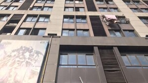 Un edificio de varios pisos con un diseño arquitectónico moderno, que presenta una serie de ventanas y unidades de aire acondicionado en la fachada.