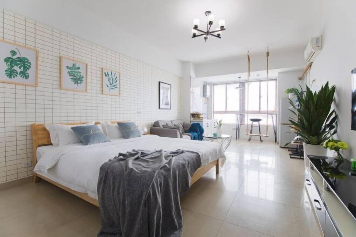 A modern bedroom with a large bed, a desk, and a chair.