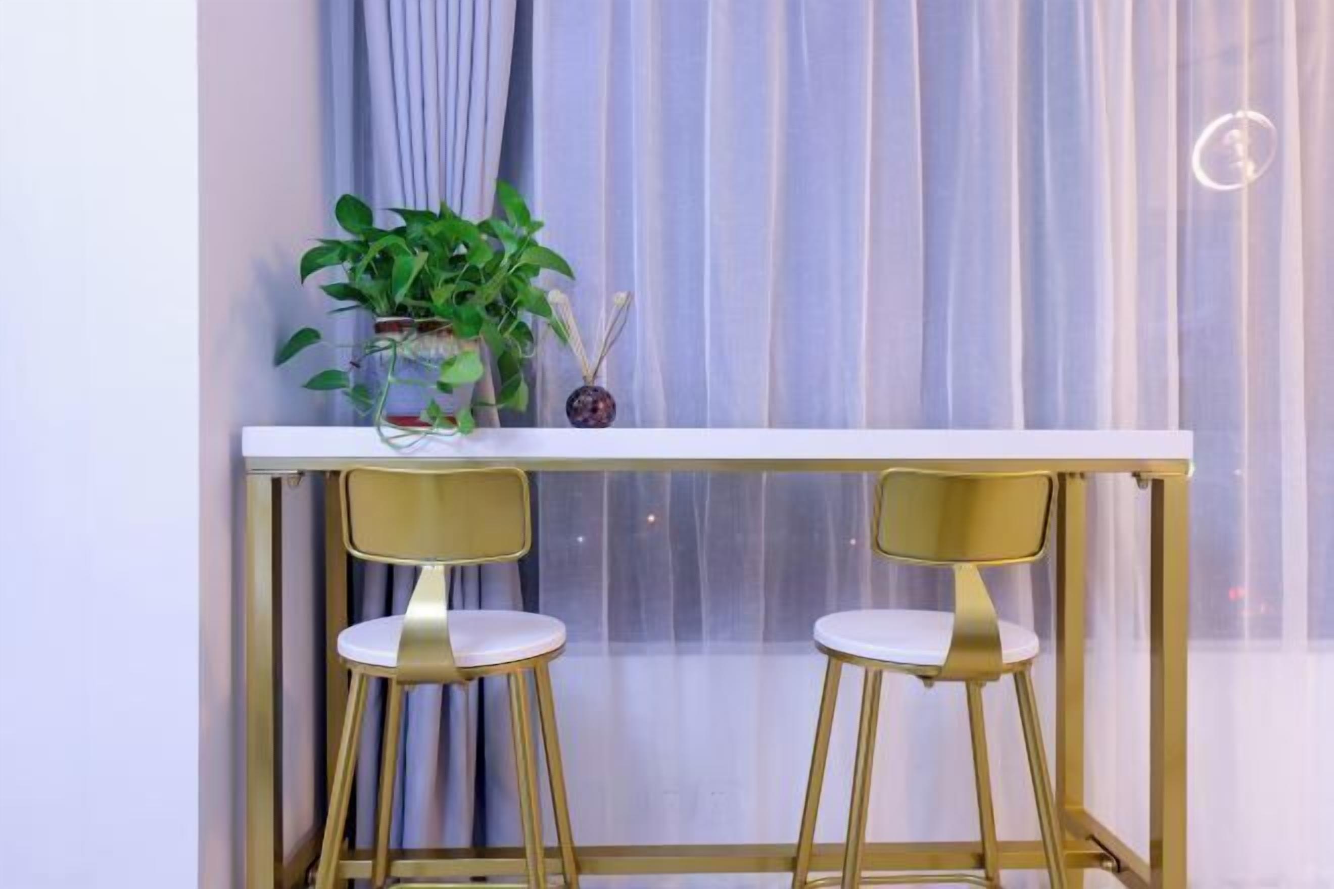 A small table with two gold chairs, a potted plant, and a decorative item on the table.