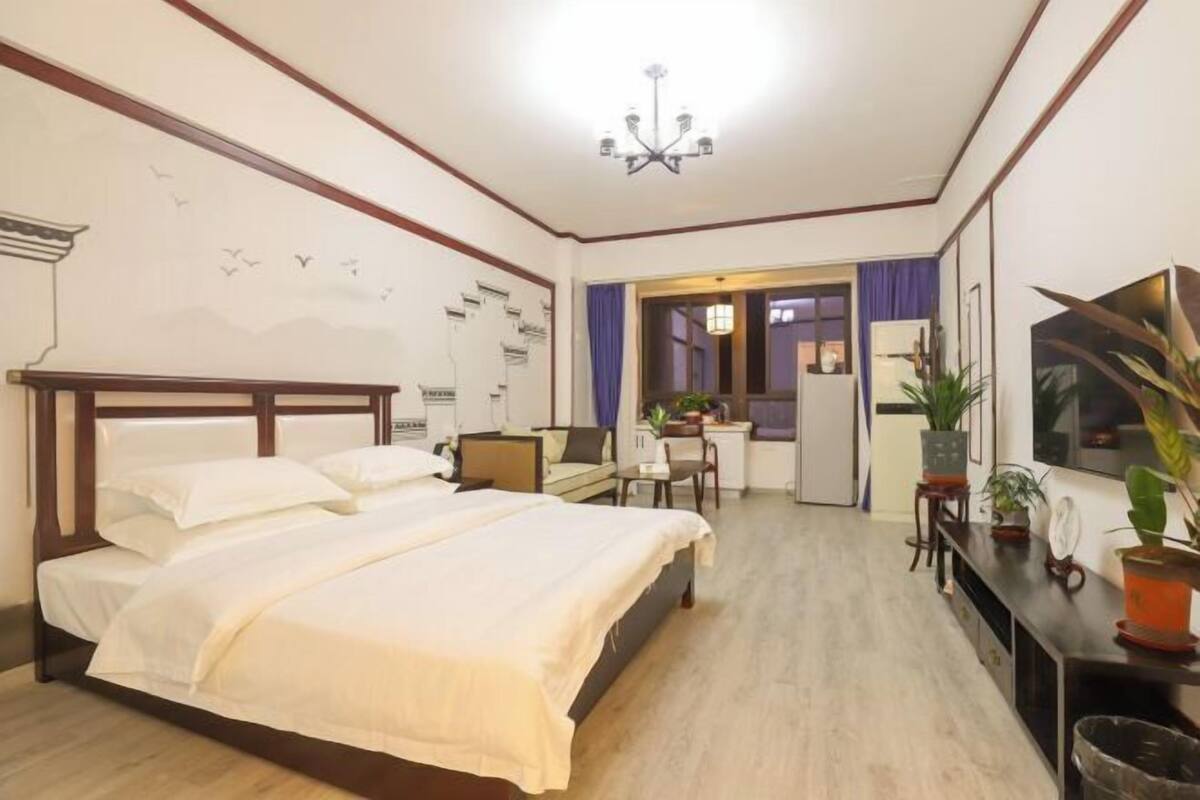 A hotel room with a large bed, a desk, a chair, and a TV.