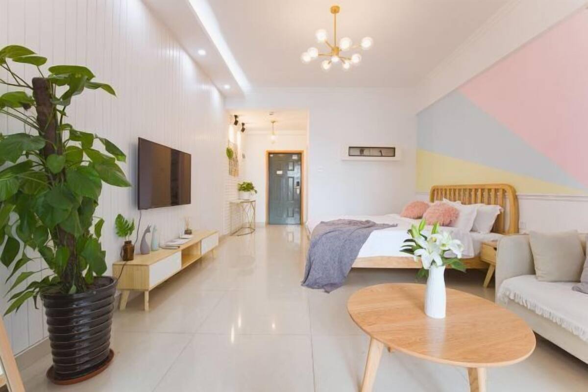 A modern bedroom with a bed, bedside table, and a potted plant.