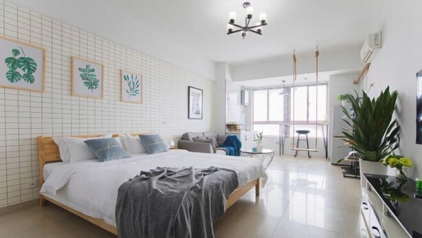 Un dormitorio moderno con una cama grande, un escritorio pequeño y un área de comedor con vistas al exterior.
