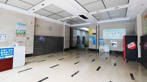 Un vestíbulo moderno y limpio con piso de baldosas, una recepción y carteles informativos en las paredes.