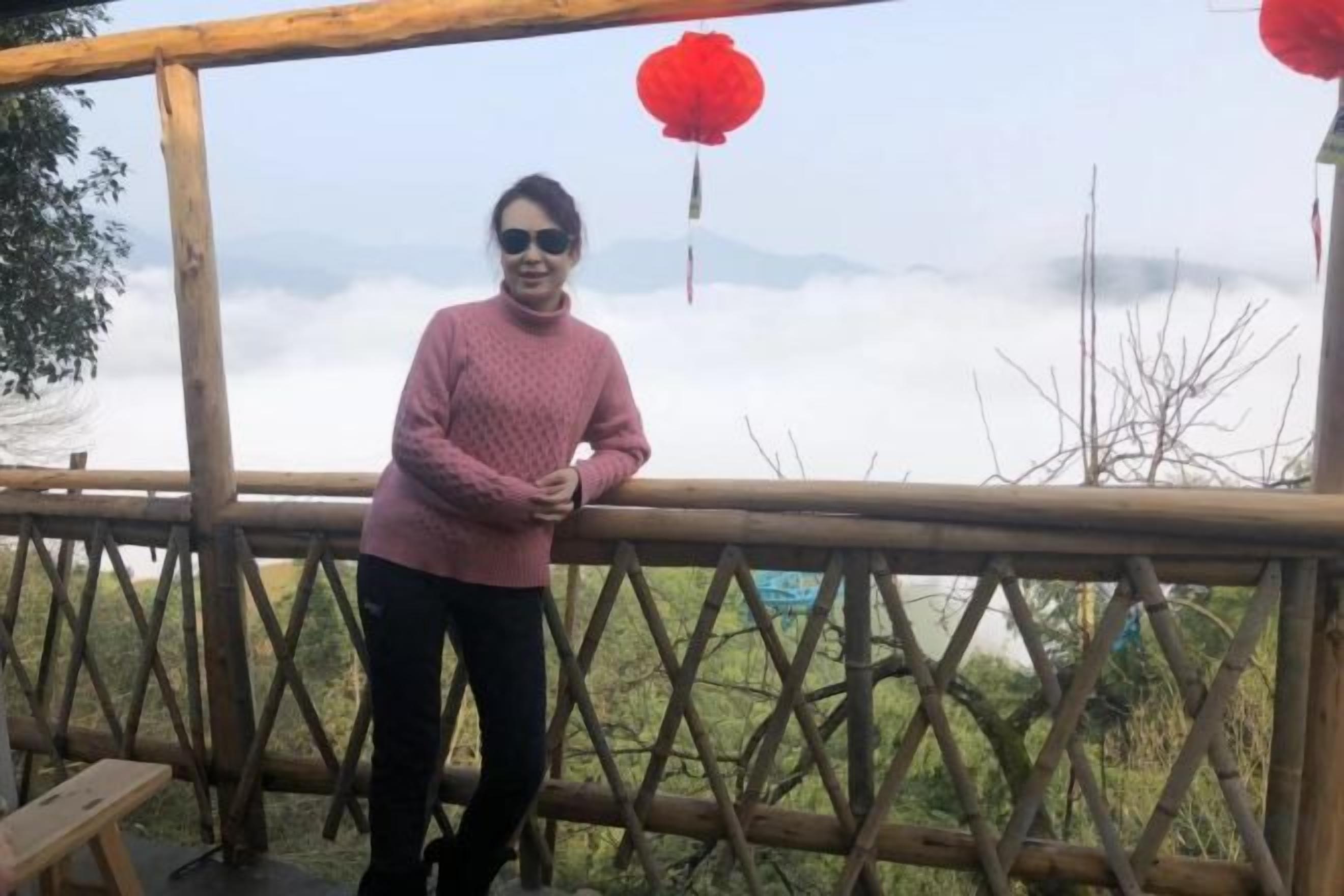A person standing on a wooden deck with a view of a mountainous landscape.
