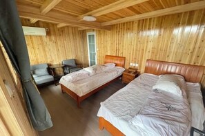 A wooden-paneled room with two beds, a chair, and a small table. - Mulihong Yuanwei Inn (Xiuning)