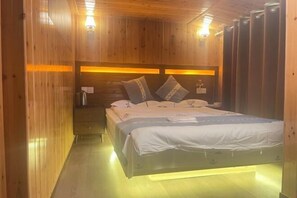 A wooden-paneled room with a bed, bedside table, and wall-mounted light fixtures. - Mulihong Yuanwei Inn (Xiuning)