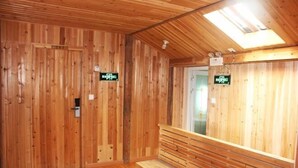 A wooden sauna room with benches and signs indicating the sauna and changing rooms. - Mulihong Yuanwei Inn (Xiuning)