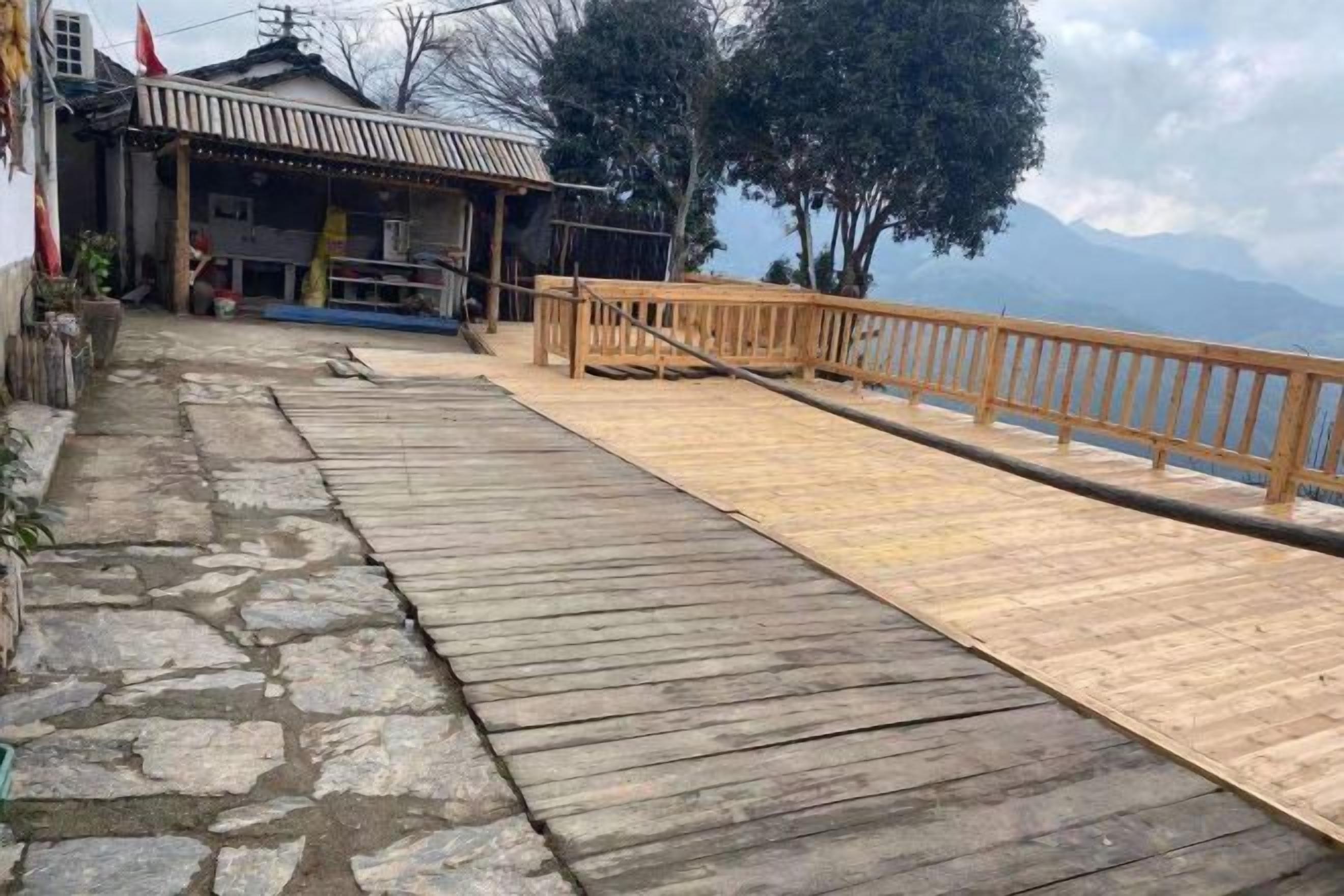 A wooden bridge leading to a traditional building with a stone pathway.