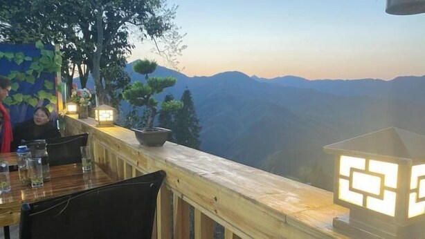 A restaurant with a wooden deck overlooking a mountainous landscape. - Mulihong Yuanwei Inn (Xiuning)