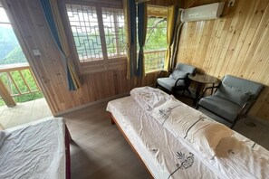 A wooden-paneled room with a bed, two chairs, and a small table. - Mulihong Yuanwei Inn (Xiuning)