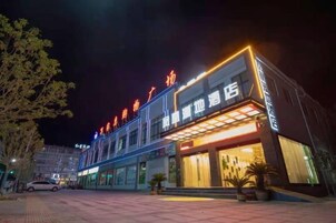 Un hotel con fachada moderna, amplias ventanas y una entrada bien iluminada.