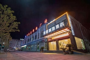 Et hotel med en moderne facade, store vinduer og en veloplyst indgang.