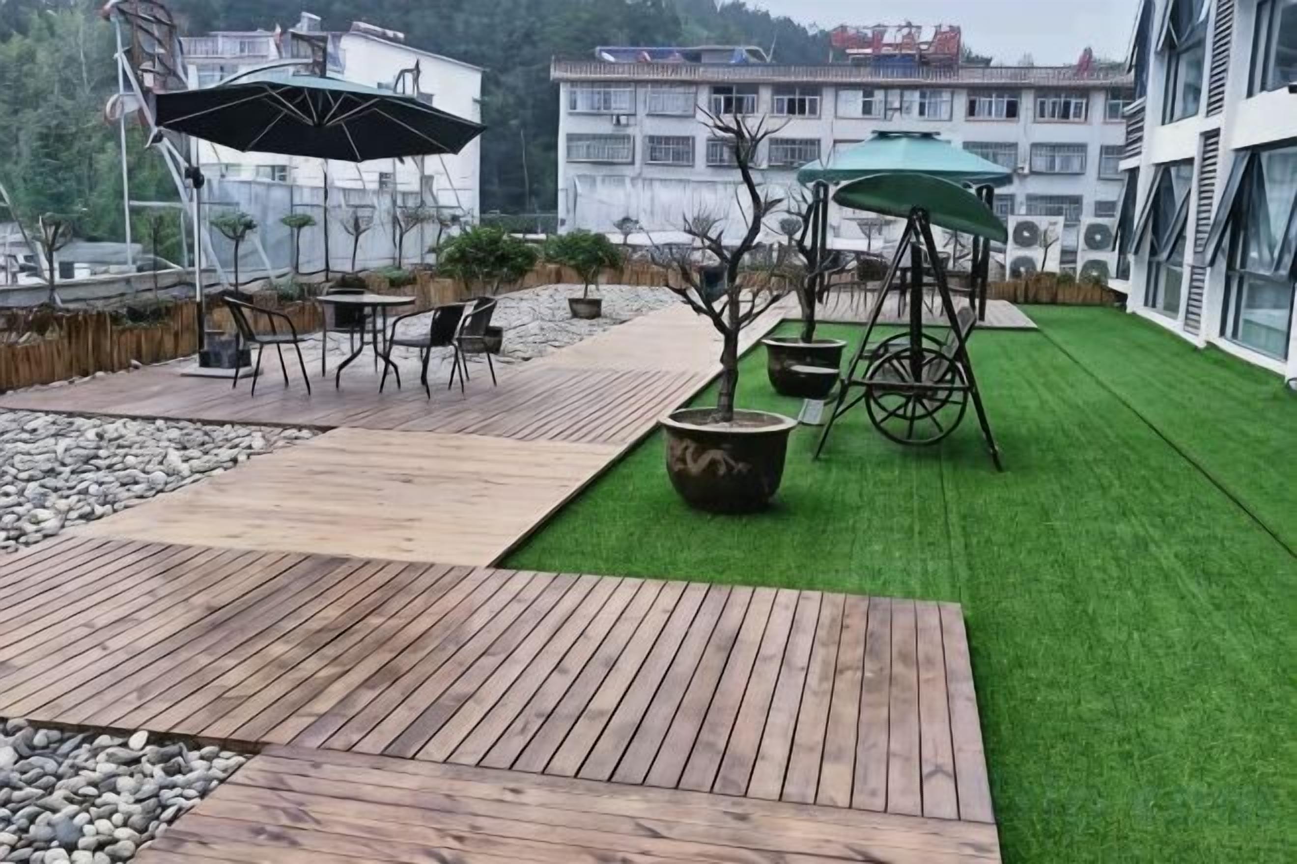 Terraza en la azotea con suelo de madera, mobiliario exterior y césped artificial verde.