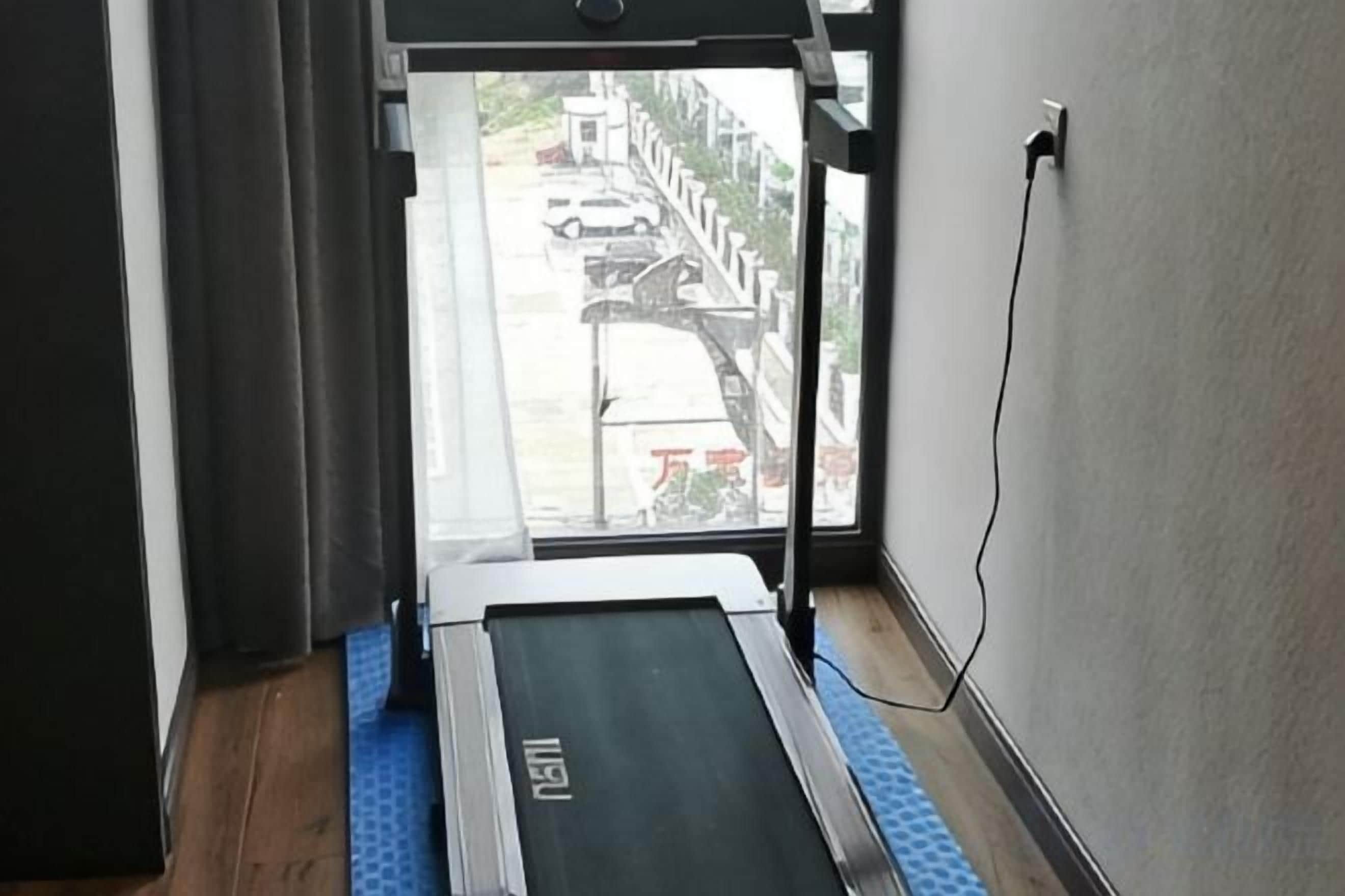 Una cinta de correr en una habitación con ventana que da a la calle.