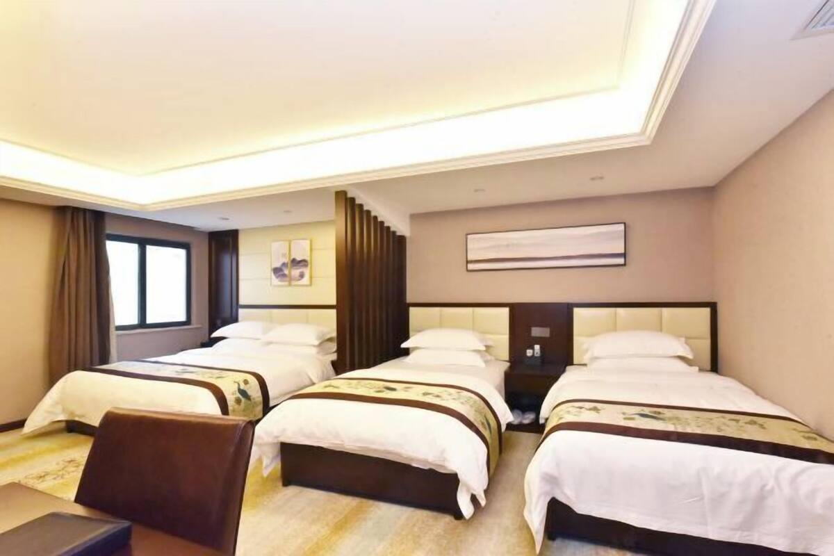 A hotel room with two beds, a desk, a chair, and a large window.