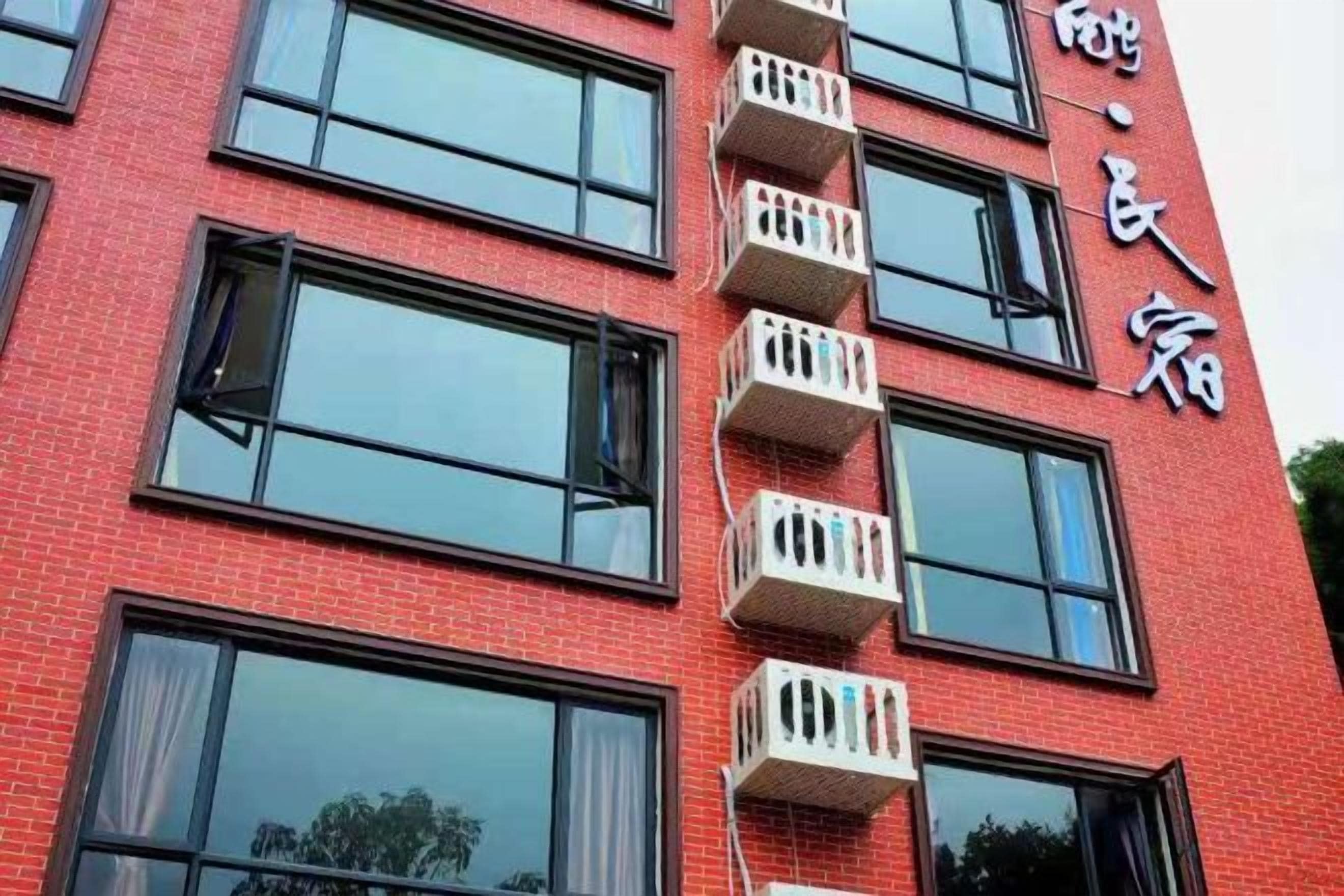 A red brick building with multiple balconies and large windows.