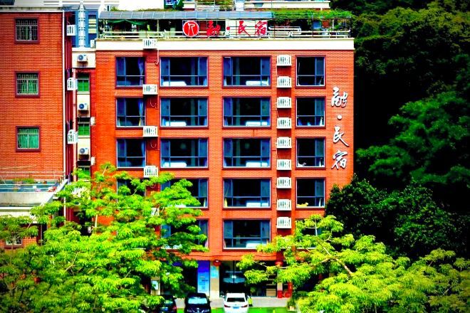 A multi-story building with a red facade, multiple windows, and balconies.