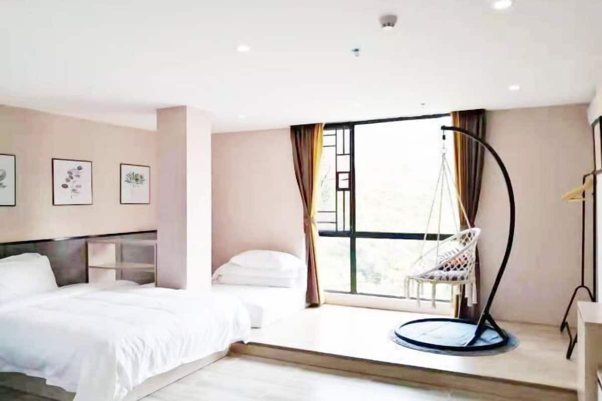 A bedroom with a bed, a hanging chair, and a window with curtains.