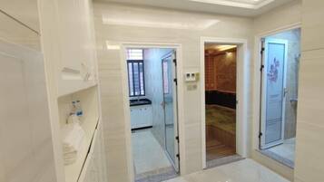Een moderne hotelkamer met een badkamer, een kleine kitchenette en een apart toilet.