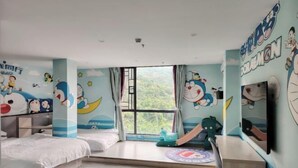 Een kinderkamer met een groot raam, stapelbedden, een televisie en decoraties met tekenfilms.