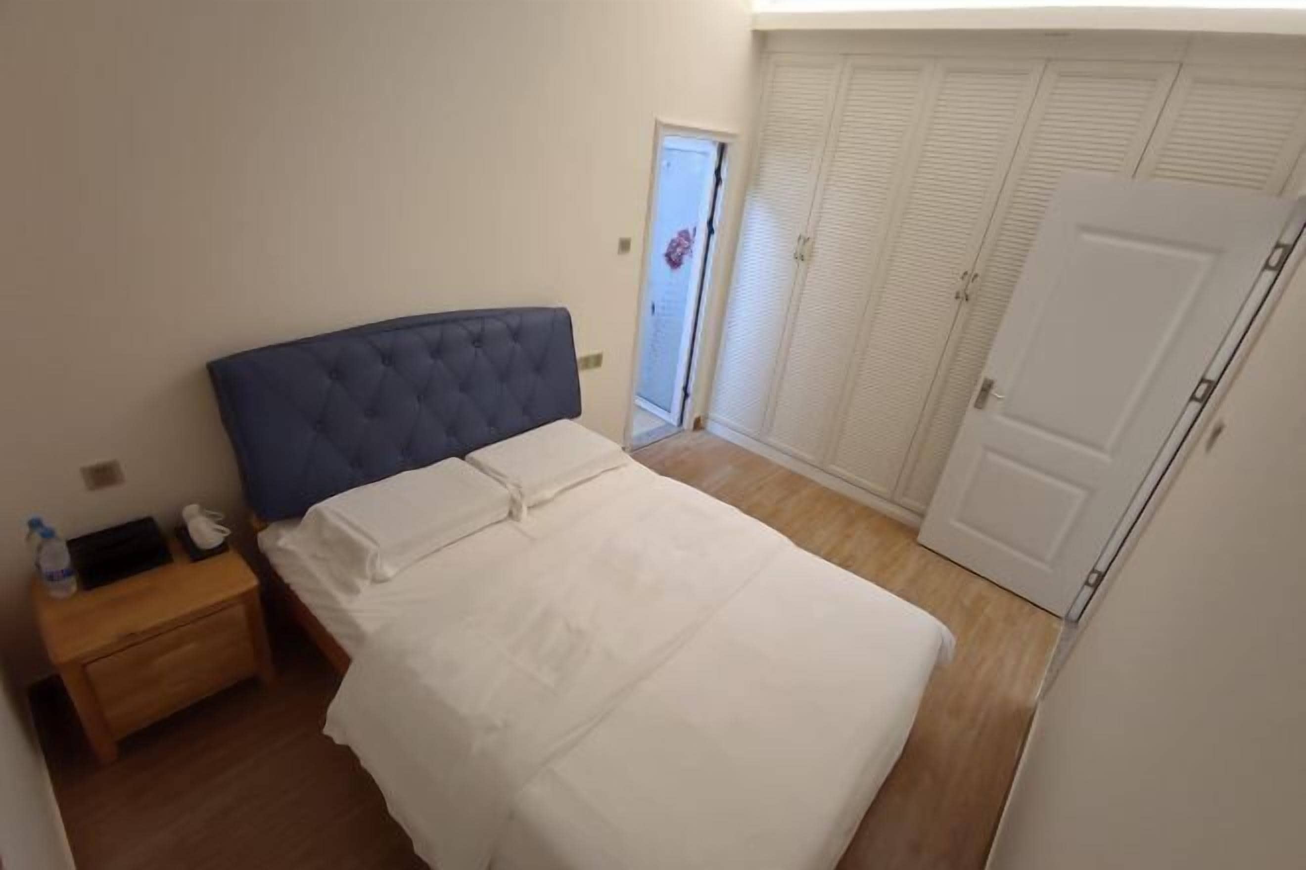 A bedroom with a bed, a nightstand, a wardrobe, and a door to a balcony.