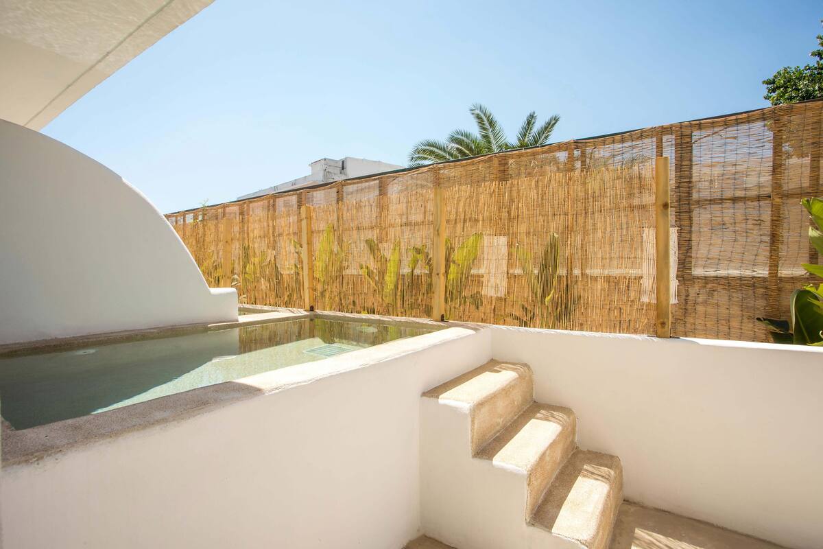 A modern outdoor pool area with a bamboo fence, a clear pool, and a set of stone steps leading up to the pool.