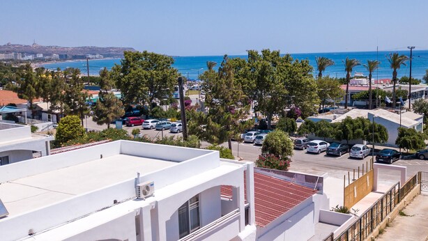 Zona residencial costera con aparcamiento, edificios y vista al mar.