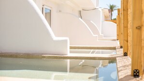 A pool area with steps leading into the water, surrounded by white walls and wooden pillars. - ATMA BEACH ROOMS & SUITES (Rhodes)