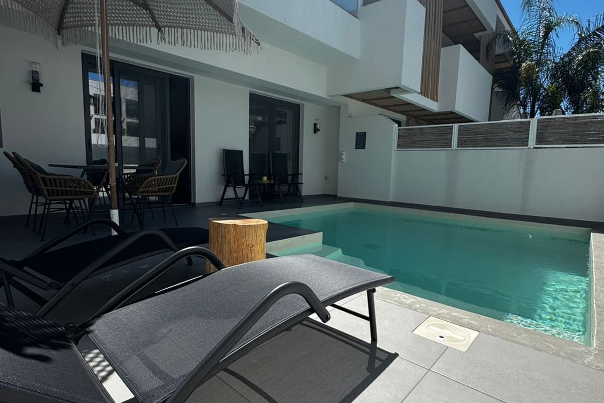 Ein moderner Poolbereich im Freien mit Liegestühlen, einer überdachten Sitzgelegenheit und freiem Blick auf den Pool.