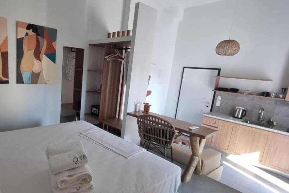 Ein modernes Hotelzimmer mit einem großen Bett, einem kleinen Schreibtisch, einer Küchenzeile und abstrakter Kunst an den Wänden.