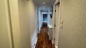 Ein Korridor mit gemusterten Wänden, Holzboden und weißen Türen.