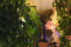 Un espai interior amb vegetació i flors, una taula i cadires.