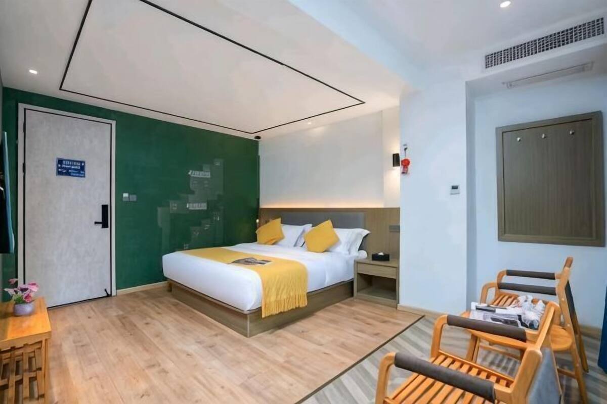 Una habitación de hotel con cama, mesita de noche, silla y puerta.