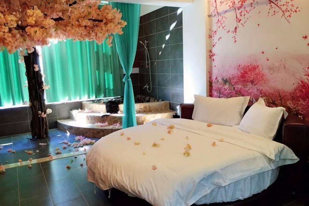 Un dormitorio con una cama grande, zona de ducha y vistas a una cortina verde.