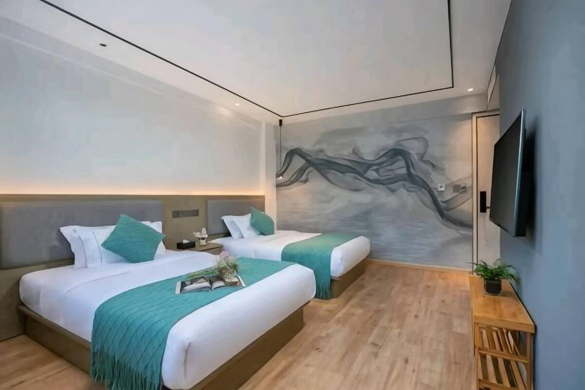 Una habitación de hotel moderna con dos camas, un televisor de pantalla plana y un mural en la pared.
