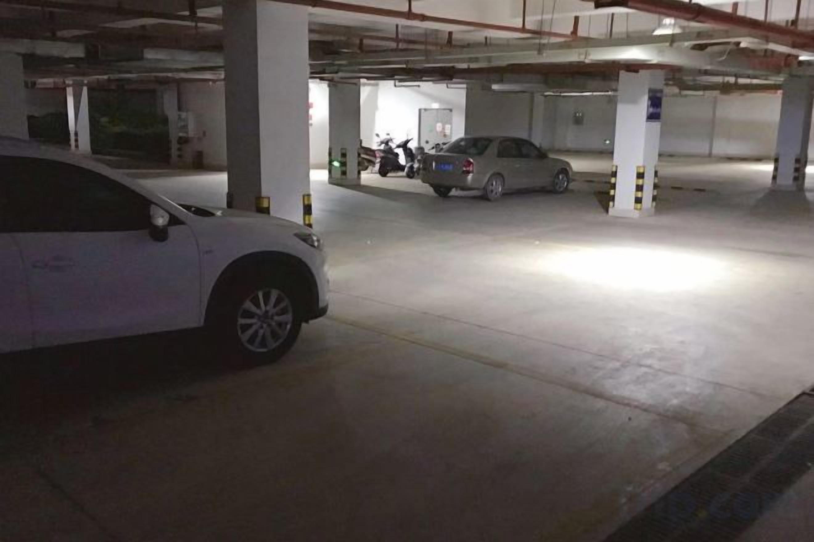 Un estacionamiento con automóviles y una motocicleta, pilares de concreto y un ambiente limpio e iluminado.