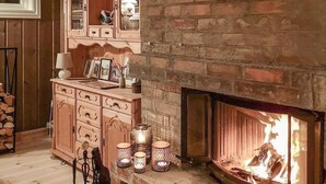 Une pièce chaleureuse avec une cheminée en briques, des meubles en bois et des bougies décoratives.