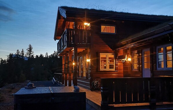 A wooden cabin with a balcony, a porch, and a visible staircase leading to the upper level.