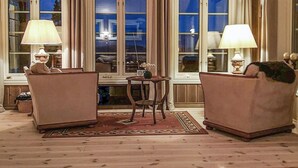 Une pièce confortable avec deux fauteuils, une petite table ronde et une fenêtre avec des rideaux.