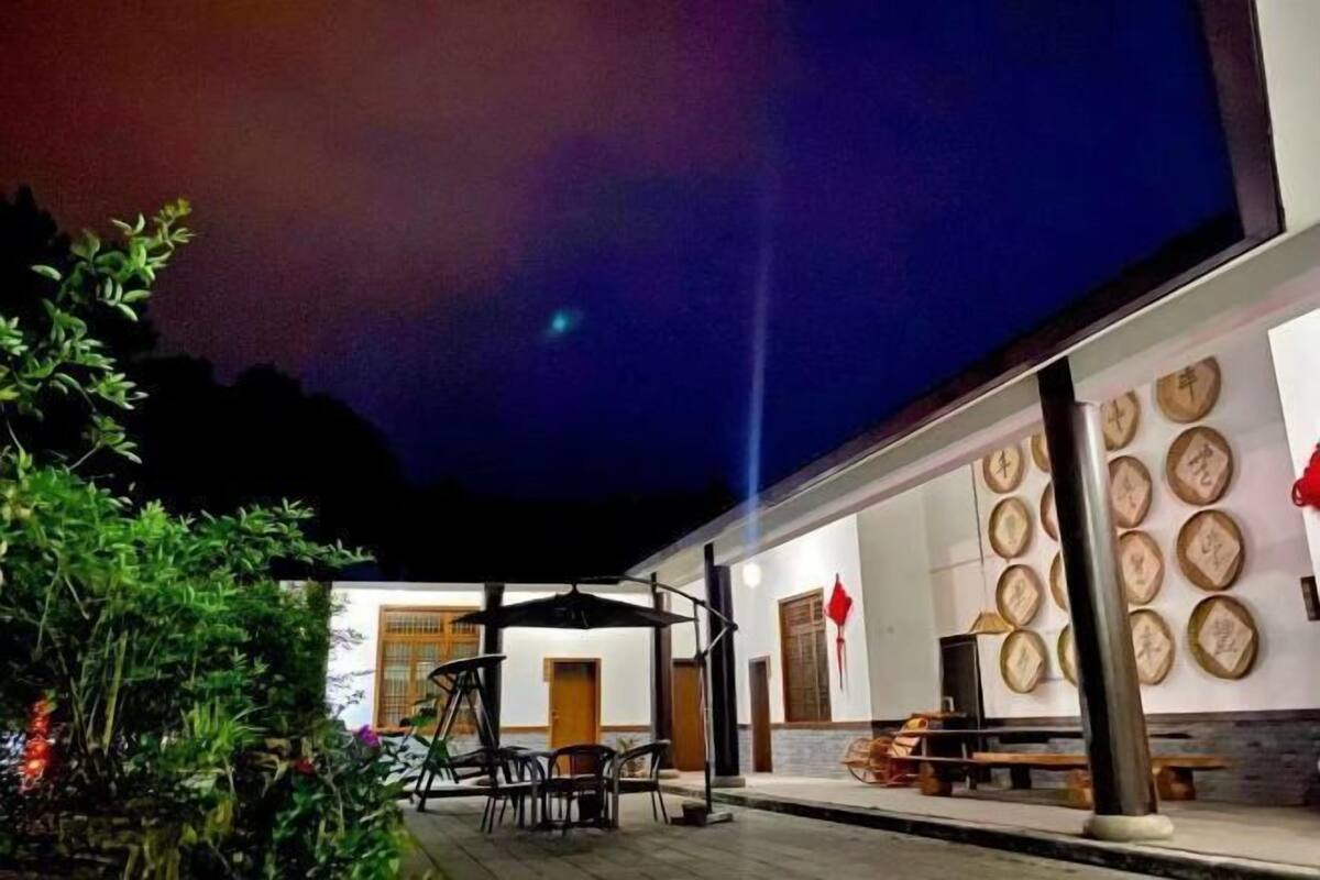 A building with a covered outdoor seating area, a wall with circular frames, and a clear night sky.