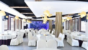 A banquet hall with round tables and white chairs, large windows, and hanging spherical light fixtures. - Mufu Leisure Mountian Resort (Muchuan)