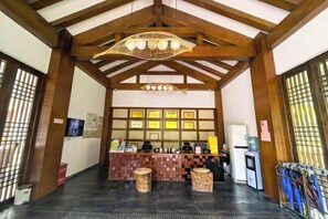 A reception area with a counter, framed certificates, a refrigerator, and a television. - Mufu Leisure Mountian Resort (Muchuan)