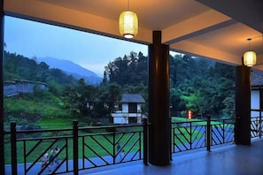 A balcony with a view of a mountainous landscape, a railing, and a hanging light fixture. - Mufu Leisure Mountian Resort (Muchuan)