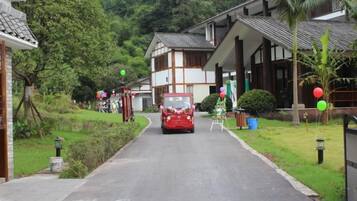 A street with traditional buildings, a red car, and greenery.