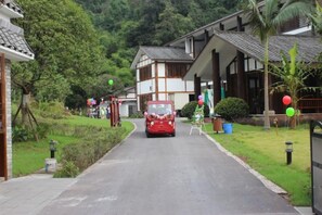 A street with traditional buildings, a red car, and greenery. - Mufu Leisure Mountian Resort (Muchuan)