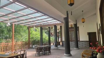 A covered outdoor area with wooden furniture and hanging lanterns.