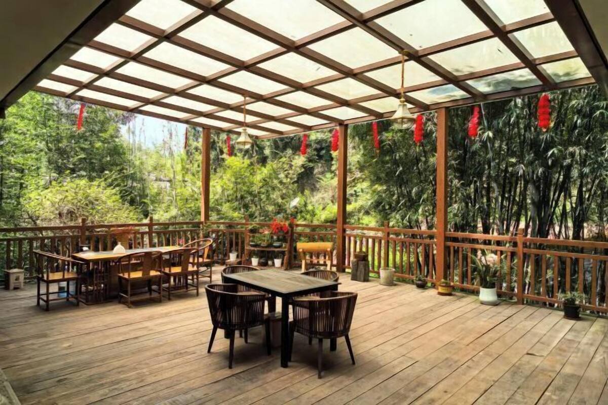 A wooden deck with a glass ceiling, surrounded by lush greenery.